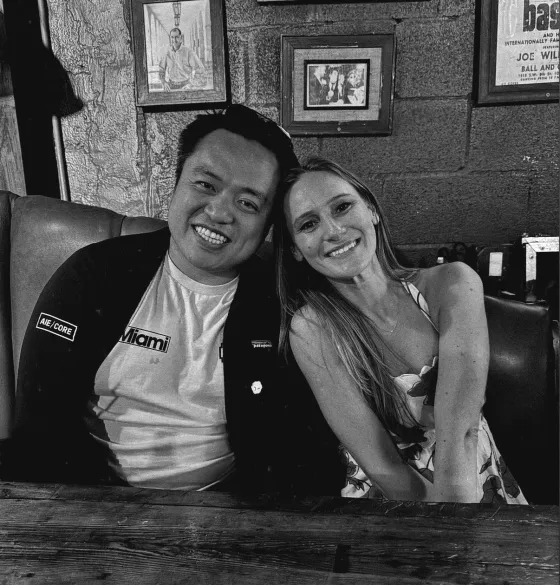 Black-and-white portrait of swyx and Michelle Bakels smiling at a table