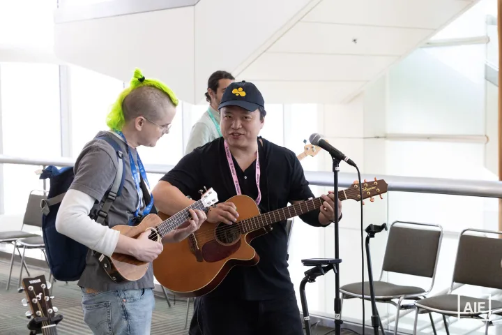 swyx playing acoustic guitar alongside another musician at AI Engineer World’s Fair 2026